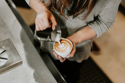 Pouring milk into a coffee in a café